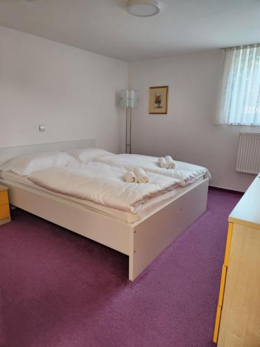 - un lit blanc dans une chambre avec moquette violette dans l'établissement Apartma Nika, à Planina