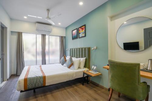 a bedroom with a bed and a mirror and a chair at Apex Beacon Hotel, Mumbai in Mumbai