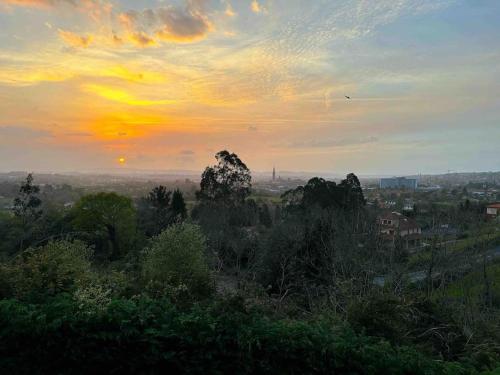 a view of a sunset from a hill with trees at Soleada in Gijón