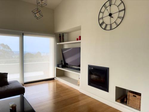 a living room with a clock on the wall and a fireplace at Soleada in Gijón