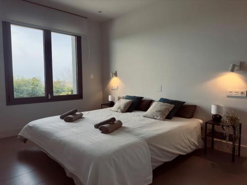 a bedroom with a large white bed with two large windows at Soleada in Gijón