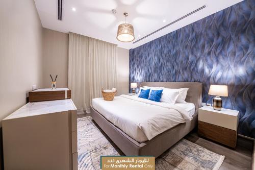 1 dormitorio con cama y pared azul en Mabaat - Obhour - 358, en Yeda