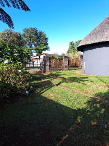 a yard with a white building and a fence at Horizon View Chalets in Graskop