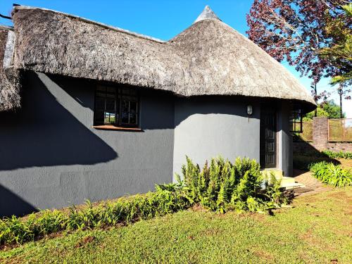 a black and white house with a thatched roof at Horizon View Chalets in Graskop