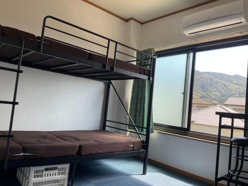 a bunk bed in a room with a window at ゲストハウスKOIZUMI in Oshima