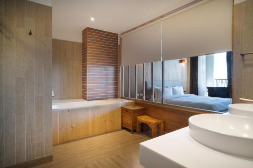 ein Bad mit einer Badewanne, einem Waschbecken und einem Bett in der Unterkunft 畫日風尚會館Sinasera Resort in Changbin