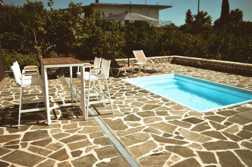 una piscina con mesa y sillas junto a una piscina en Blue in Green North, en Kastrosikia