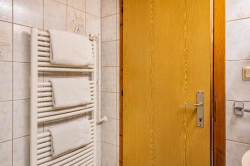 a bathroom with a towel rack and a yellow door at Adlerhorst Amsel in Santa Valpurga