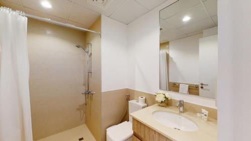 a bathroom with a sink and a toilet and a mirror at Primestay - Una Apartment Studio in Town Square in Dubai