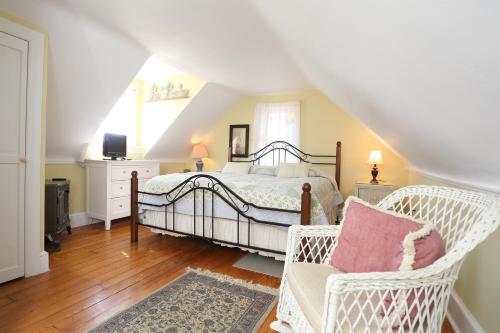 a bedroom with a bed and two wicker chairs at Beauclaires Bed & Breakfast in Cape May