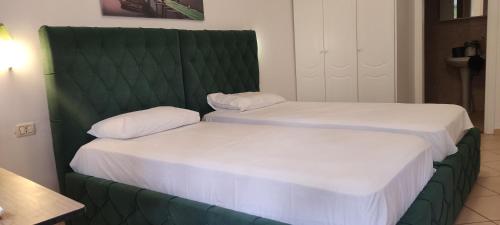 two beds in a room with a green headboard at Apartment Rina in Sarandë