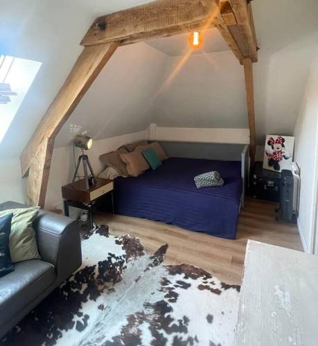 - une chambre mansardée avec un lit et un canapé dans l'établissement Appartement Cosy et charmant, à Saint Lo