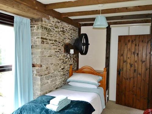 a bed in a room with a brick wall at Mill Cottage in Fowey