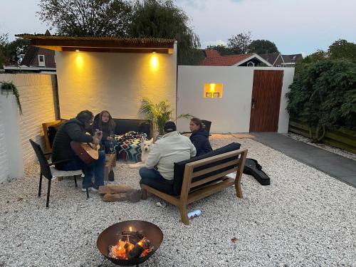 un groupe de personnes assises autour d'un foyer extérieur dans l'établissement Casa TX21, à Den Burg