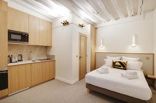 une chambre avec un grand lit blanc et une cuisine dans l'établissement Pick A Flat's Apartments in Louvre - Rue Saint Honoré, à Paris