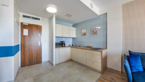 a kitchen with white cabinets and a blue wall at Olympic Park I, Sun & Snow in Kołobrzeg
