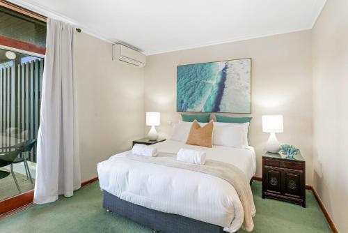 a bedroom with a large white bed and a window at The Lookout in Coffs Harbour