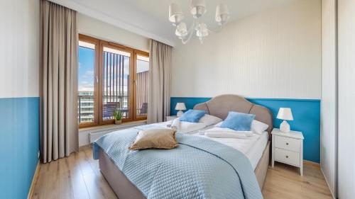 a blue and white bedroom with a bed and a window at Olympic Park I, Sun & Snow in Kołobrzeg