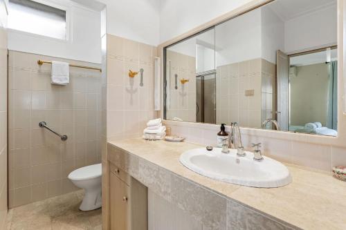 W łazience znajduje się umywalka, toaleta i lustro. w obiekcie The Lookout w mieście Coffs Harbour