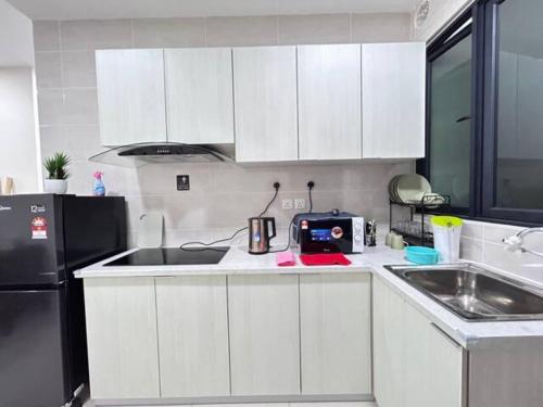 a kitchen with white cabinets and a black refrigerator at Jeff and Ricky Homestay 69 @P Residence in Kuching
