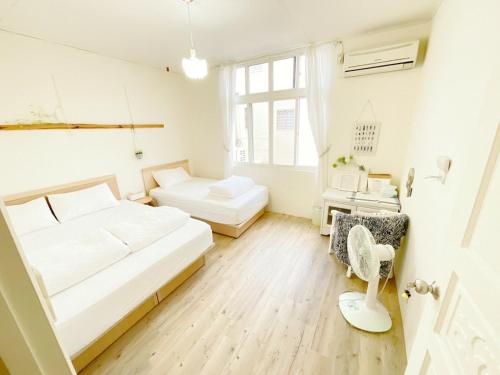 a white bedroom with two beds and a chair at 清清長屋包棟民宿 Ding House in Hengchun