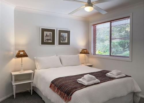 een slaapkamer met een bed met twee nachtkastjes en twee lampen bij On the Hillside in Coffs Harbour