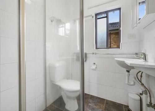 a white bathroom with a toilet and a sink at Ocean Sands 5 in Sawtell