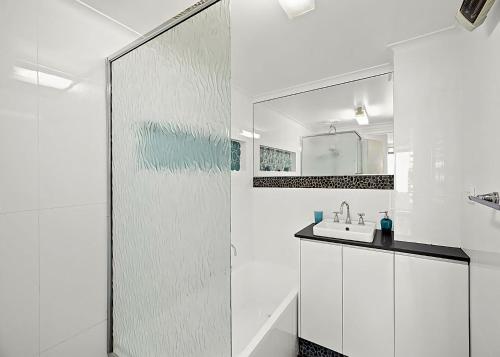 ein weißes Badezimmer mit einem Waschbecken und einem Spiegel in der Unterkunft Ocean Waves in Nambucca Heads