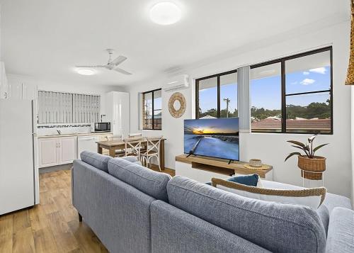 a living room with a blue couch and a kitchen at Blue Gem in Sawtell