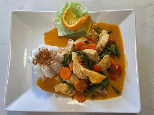 a plate of food with chicken and rice and an orange slice at Yaberg Affären in Hyltebruk