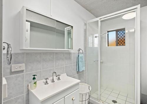 a white bathroom with a sink and a shower at Driftwood Court 1 in Sawtell