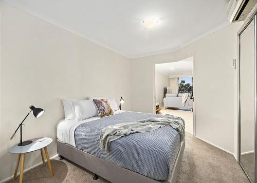 a white bedroom with a bed and a table at Ocean Pines in Nambucca Heads