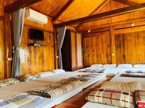 Un grupo de 4 camas en una habitación con paredes de madera en A Khoan Homestay - Venuestay, en Mai Chau
