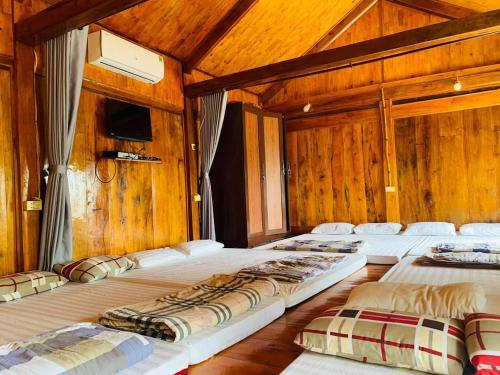 a group of four beds in a room with wooden walls at A Khoan Homestay - Venuestay in Mai Chau