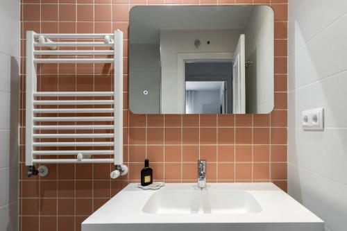 een badkamer met een witte wastafel en een spiegel bij Aspasios Calle Mayor Apartments in Madrid