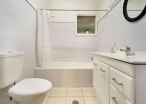 a white bathroom with a toilet and a sink at Driftway in Urunga