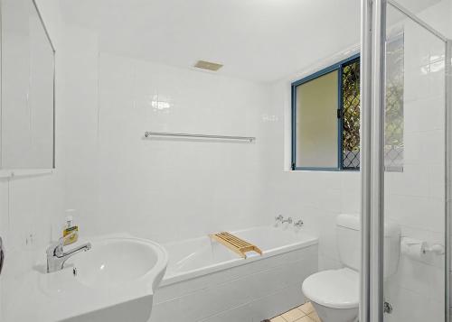 a white bathroom with a tub and a toilet and a sink at Waters Edge in Nambucca Heads