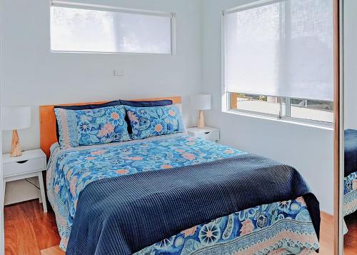 1 dormitorio con 1 cama con edredón azul y 2 ventanas en Beachfront 8, en Sawtell