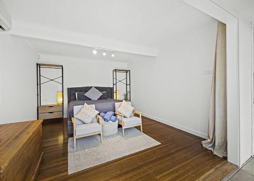 a living room with a bed and two chairs at Garden Spa Villa in Coffs Harbour