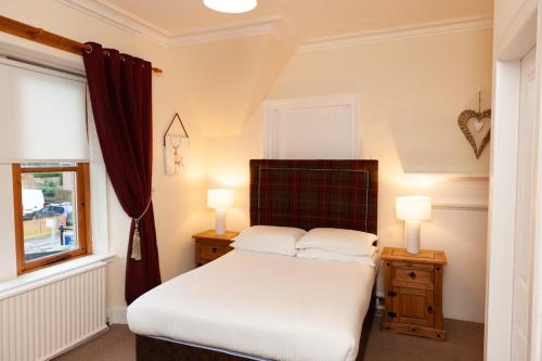 a bedroom with a bed with two night stands and two lamps at Alban and Abbey House in Inverness