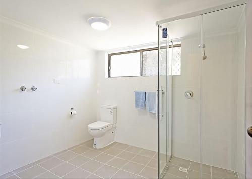 a bathroom with a toilet and a glass shower at Peninsula in Sawtell