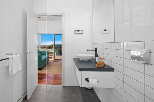 a white bathroom with a sink and a mirror at Ciao Korora in Coffs Harbour
