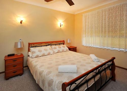a bedroom with a bed and a window at Rose Cottage in Sawtell