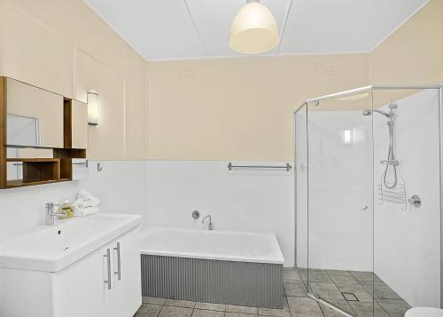 a white bathroom with a shower and a sink at Lobster Cottage in Sawtell