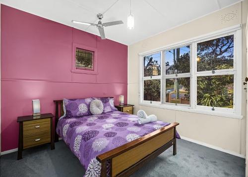 a purple bedroom with a bed and a window at Lobster Cottage in Sawtell
