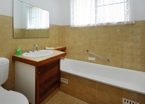a bathroom with a sink and a tub and a toilet at Rose Cottage in Sawtell