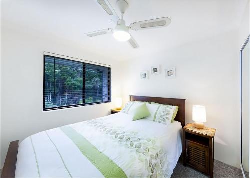 a white bedroom with a bed and a window at Periwinkle in Sawtell