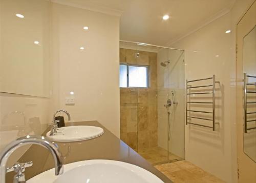 a bathroom with a sink and a glass shower at 1/17 22nd Ave - Sawtell, NSW in Sawtell
