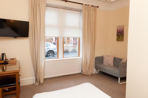 a bedroom with a window with a couch and a chair at Alban and Abbey House in Inverness