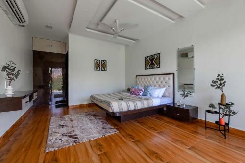 a bedroom with a bed and a wooden floor at Natures Odyssey by StayVista - Amidst lush greenery with Outdoor pool and Indoor activities in Chinchavli